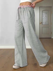 Dettaglio dei pantaloni sportivi grigi a vita alta con bordo geometrico rosso e bianco