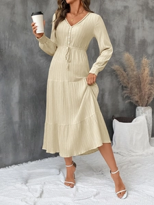 Detail of V-neck beige textured maxi dress with button accents and tiered skirt hem