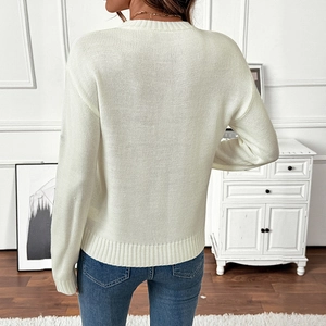 Back view of a white knitted sweater with round neck and ribbed cuffs in a home setting