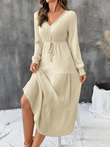 Detail of beige V-neck midi dress featuring textured fabric and waist tie design