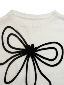Détail d'un pull blanc en maille avec nœud 3D en corde noire et col rond côtelé