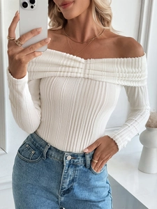 Detail of off-shoulder white knit top showing textured ribbed fabric and folded neckline