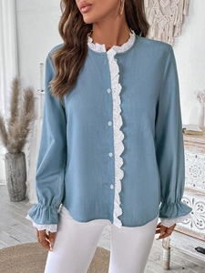Détail de la broderie en dentelle blanche sur un chemisier bleu clair à manches longues