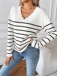 Detail des gewellten V-Ausschnitts eines weißen Strickpullovers mit schwarzen Streifen