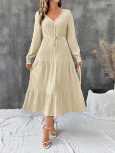 Detail of beige V-neck dress featuring lace trim, drawstring waist, and layered textured fabric