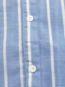 Close-up of blue and white vertical striped fabric with white buttons on the shirt