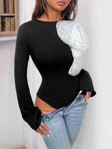 Detail of a black long-sleeve bodysuit featuring a large 3D white organza flower on the shoulder