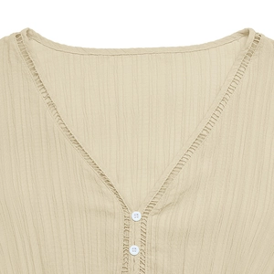 Detail of V-neckline with ladder embroidery and buttons on apricot textured fabric