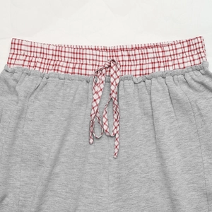 Dettaglio pantaloncini in maglia grigia con elastico in vita a scacchi rossi e lacci