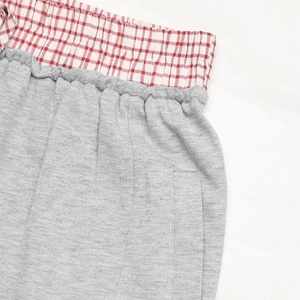 Dettaglio dei pantaloni a vita alta con cintura elastica a quadretti bianchi e rossi