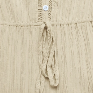 Close-up of textured V-neck dress featuring hollow lace details and waist drawstring