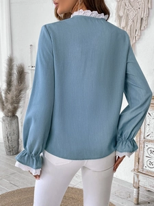 Détail de la chemise bleu clair avec poignets en dentelle et texture verticale sur la manche