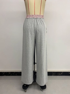 Dettaglio dei pantaloni grigi a vita alta a gamba larga con elastico e tessuto morbido