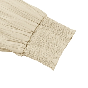 Detailed macro view of smocked elastic cuffs on beige textured long sleeve dress
