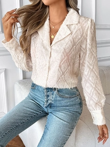 Close-up of white long sleeve shirt featuring textured feather tassel fabric and button cuffs
