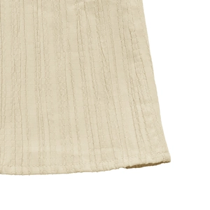 Detail of the light beige pleated fabric texture and stitching on the hem of the V-neck dress