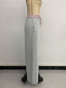 Dettaglio dei pantaloni sportivi grigio chiaro a gamba larga con elastico a scacchi rossi