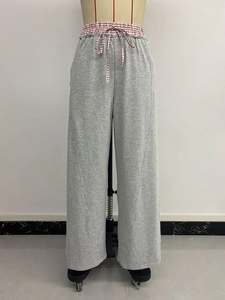 Dettaglio dei pantaloni grigi a vita alta con coulisse a quadretti rossi e bianchi in vita