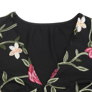 Close-up of floral embroidery on black V-neck long-sleeve top showing intricate stitch detail