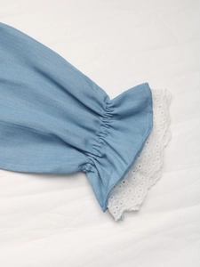 Détail de manche de chemise bleu clair avec poignet élastique et bordure en dentelle blanche