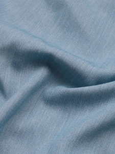 Détail du tissu bleu clair montrant le tissage délicat et les plis doux de la matière