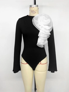 Detail of black ribbed knit bodysuit featuring a large 3D white floral shoulder applique