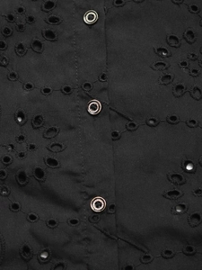 Detailed macro view of black lace eyelet fabric with decorative silver-rimmed buttons