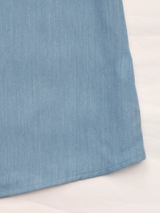 Détail de l'ourlet de chemise bleu clair avec texture sergée et coutures de haute qualité