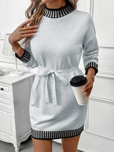 Detail of grey knit dress featuring elegant black and white striped cuffs and waist tie