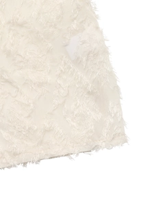 Detail shot of white shirt fabric with textured 3D floral embroidery and fringe