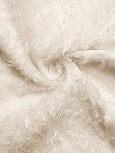 Detail of cream white shirt fabric with soft textured jacquard and 3D tufted fringe patterns