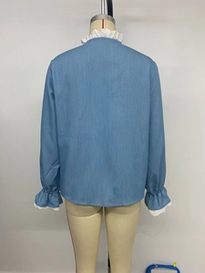 Détail de chemisier bleu à manches longues avec bordure en dentelle et poignets volantés