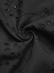 Macro shot of black Broderie Anglaise lace fabric with intricate cutout embroidery