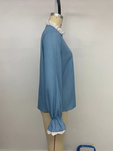 Détail d'une chemise bleu clair avec dentelle blanche sur le col et les poignets