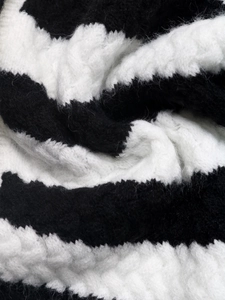 Close-up of black and white striped knit texture with thick wool cable weave detail