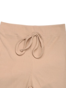 Detail of light beige ribbed knit trousers featuring an elastic waist and drawstring