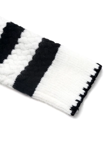 Detail of black and white striped knit sweater with cable pattern and ribbed cuff sleeve