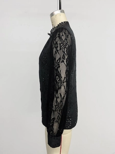 Detail of floral lace sleeve and black eyelet embroidery on a long sleeve shirt