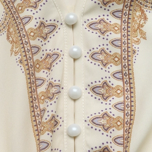 Gros plan du décolleté en V avec motif paisley et boutons de perles sur la robe