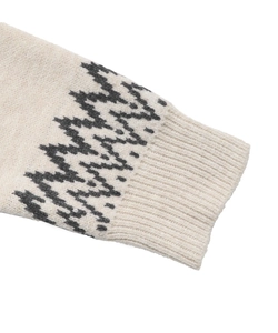 Close-up of Fair Isle knit sweater cuff with geometric patterns on soft beige fabric