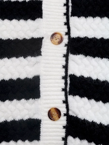 Macro detail of chunky black and white striped knit cardigan with amber buttons and texture