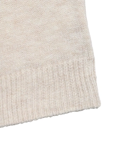 Detail of beige Fair Isle sweater showing fine knit texture and ribbed hem craftsmanship