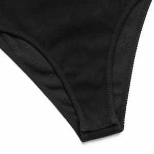 Détail de près d'un body noir côtelé montrant la fermeture à boutons-pression et le tissu