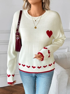 Detail of soft cream knit sweater with red heart jacquard and ribbed cuffs on sleeve