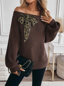Detail of off-shoulder dark brown chunky knit sweater featuring large leopard print bow
