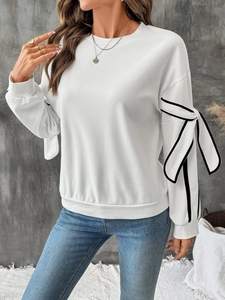 Detail of white sweatshirt sleeve featuring contrast bow ties and ribbed cuffs