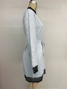 Detail of grey knitted dress featuring black and white striped cuffs and waist tie belt