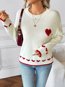 Detail of soft white knit sweater featuring red heart patterns and ribbed texture
