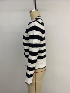 Close-up of black and white striped knit sweater with textured waffle patterns and ribbed cuffs