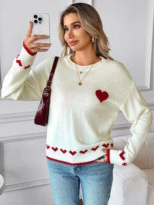 Detail of red heart jacquard pattern on white knit sweater with round neck